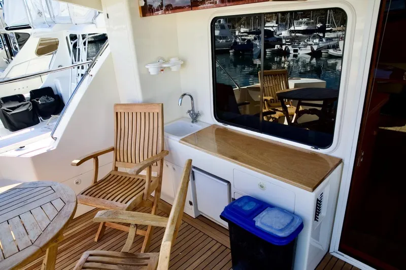 Slide: The Image of Outdoor seating area on 2002 Mikelson 50 Sportfisher yacht with wooden chairs and table. - 35