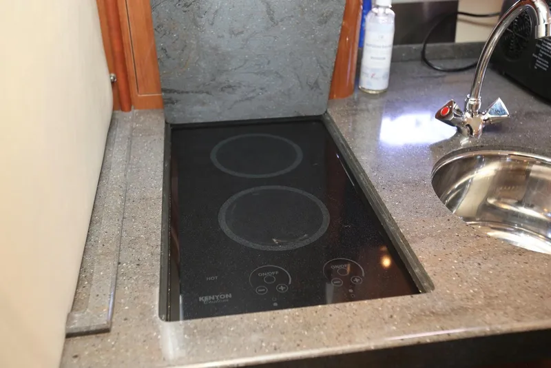 Slide: The Image of 2012 Regal 35 Sport Coupe kitchen with Kenyon electric cooktop and stainless steel sink. - 101