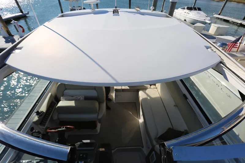 Slide: The Image of 2012 Regal 35 Sport Coupe interior view with seating and helm, docked by the water. - 74
