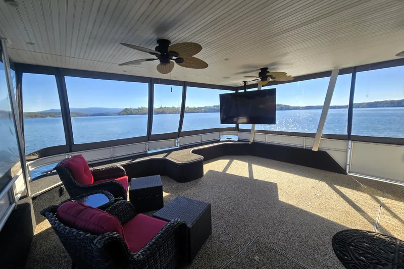 Slide: The Image of Luxurious 2013 Thoroughbred houseboat interior with lake view, featuring seating, TV, and ceiling fans. - 15
