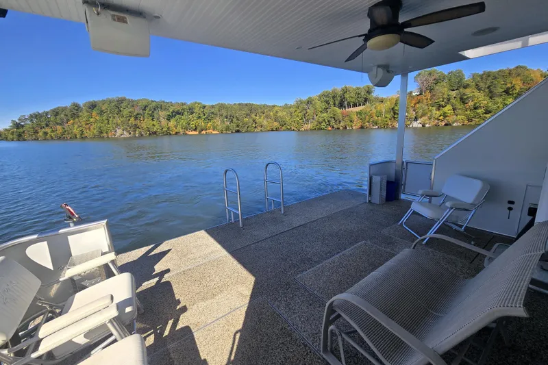 Slide: The Image of 2013 Thoroughbred 80'x 18' houseboat deck with chairs, overlooking serene lake and lush greenery. - 19