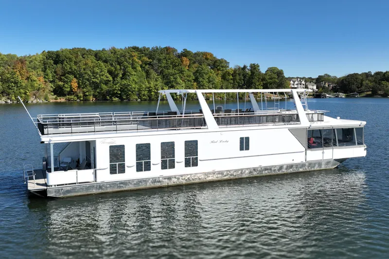 Slide: The Image of 2013 Thoroughbred houseboat on a serene lake with lush green shoreline. - 2
