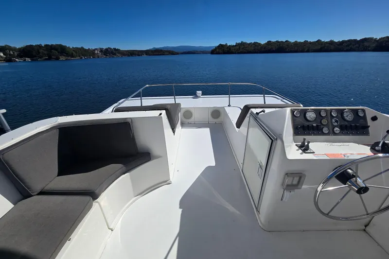 Slide: The Image of 2013 Thoroughbred 80'x 18' boat helm with seating, overlooking serene lake and distant shoreline. - 8