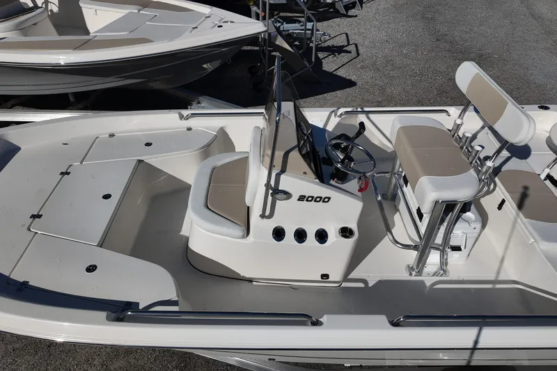 Slide: The Image of 2025 Bulls Bay 2000 boat with beige seating and steering console, docked outdoors. - 7