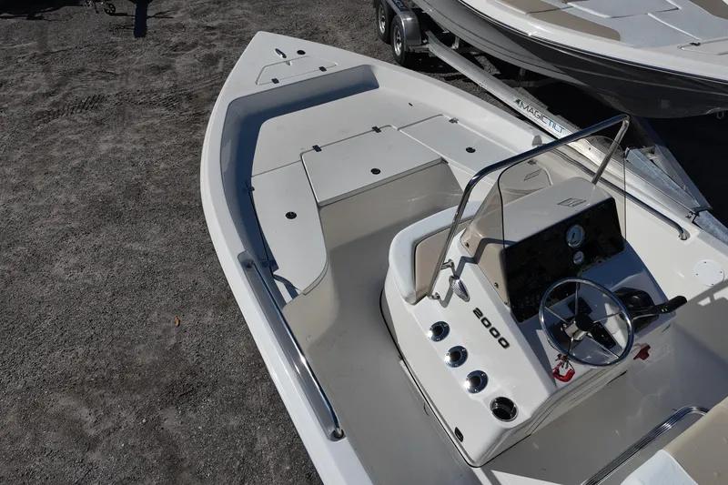 Slide: The Image of 2025 Bulls Bay 2000 boat interior with steering console and seating, parked on gravel. - 8