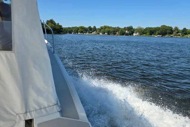 Slide: The Image of 1984 Bayliner 2802 Trophy cruising on a serene lake with scenic shoreline views. - 28