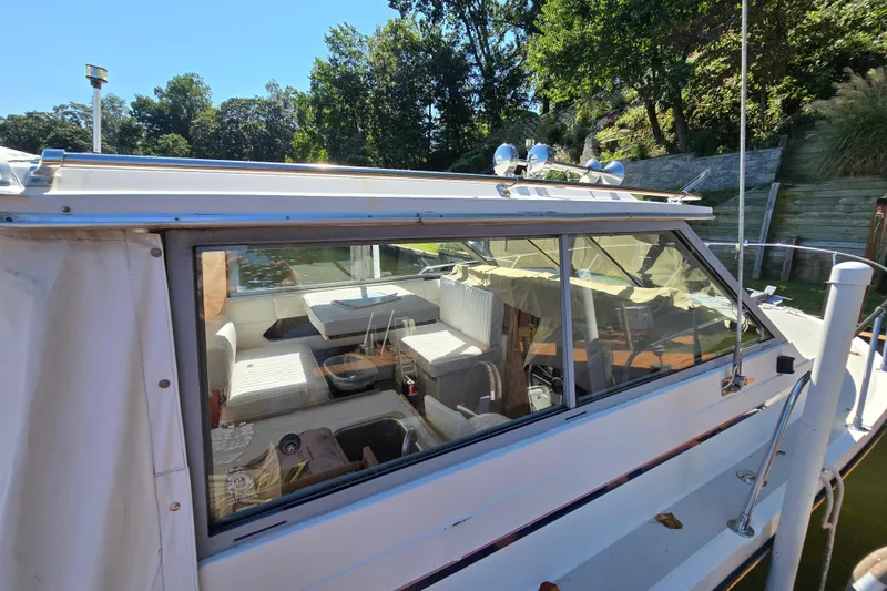 Slide: The Image of 1984 Bayliner 2802 Trophy boat docked, showing interior seating and windows. - 9