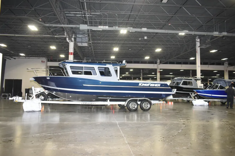 The Image of 2026 KingFisher 2825 Coastal Express boat displayed indoors on a trailer. - 9