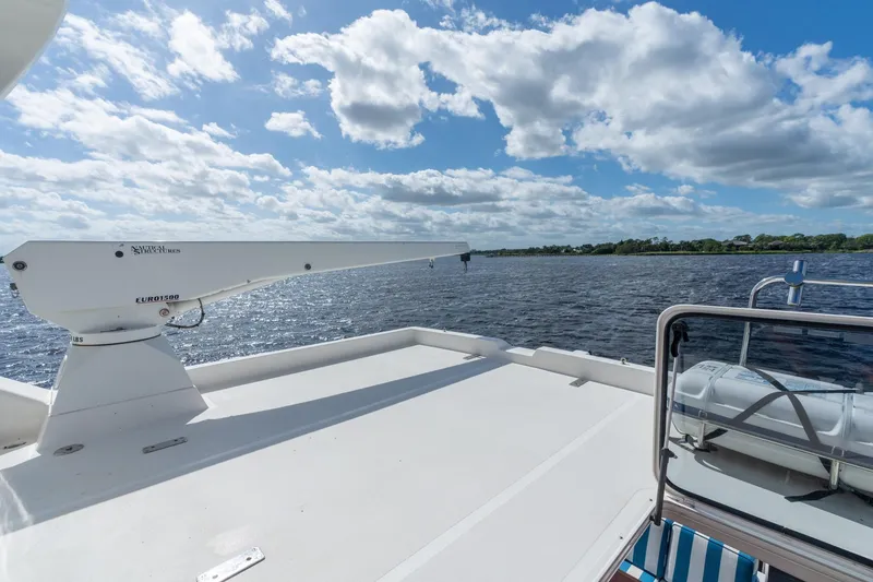 Slide: The Image of 2009 Pacific Mariner 65 Motoryacht deck with crane, overlooking serene water and sky. - 12