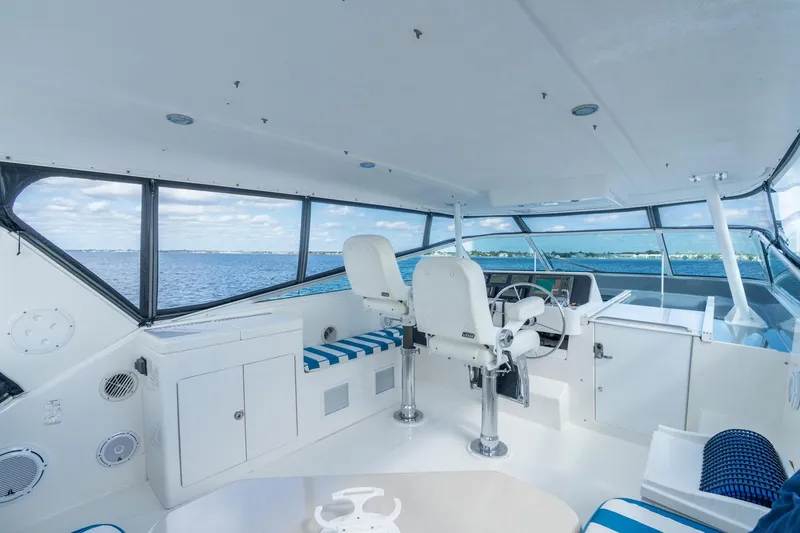 Slide: The Image of 2009 Pacific Mariner 65 Motoryacht helm with ocean view, featuring white and blue seating. - 16