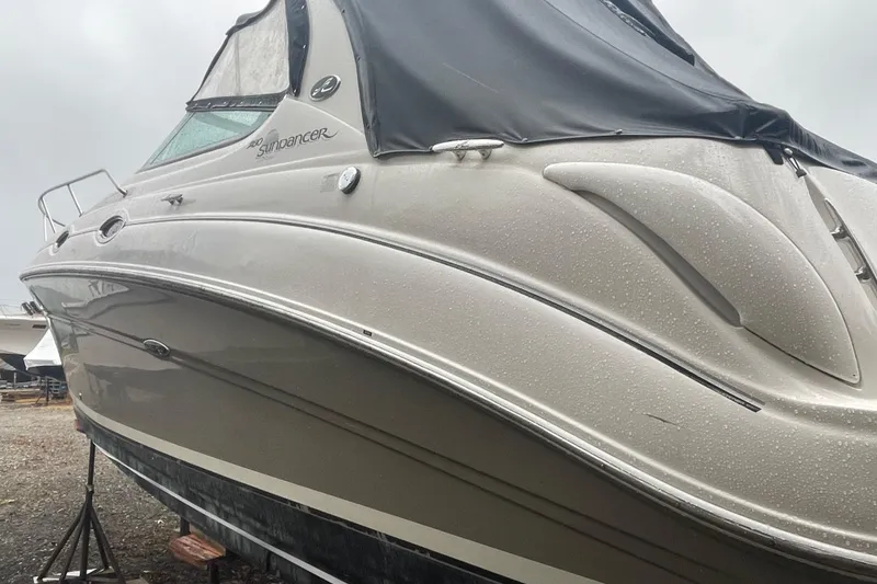 Slide: The Image of 2006 Sea Ray Sundancer 280 boat with sleek design, covered in raindrops, docked outdoors. - 18