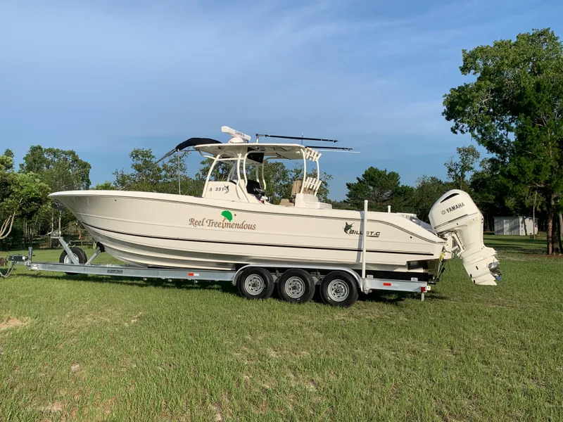 Slide: The Image of 2016 Key West 351 Billistic boat on a trailer in a grassy area. - 2