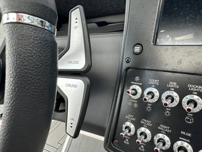 Slide: The Image of 2024 Moomba Max boat dashboard with cruise control and light switches. - 30