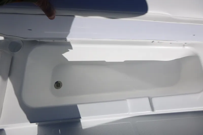 Slide: The Image of 2026 Tahoe T18 boat storage compartment with drain plug, open lid view. - 13
