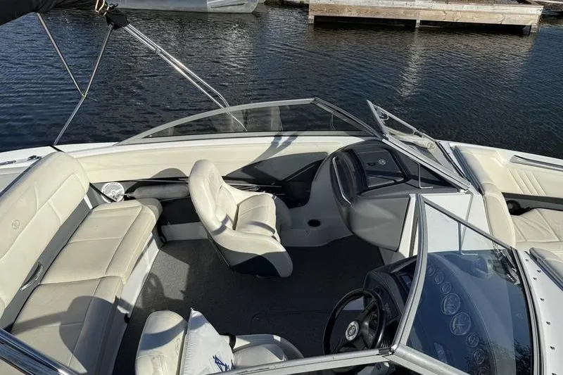 Slide: The Image of 2008 Cobalt 202 boat interior with white seating and steering wheel, docked on calm water. - 2