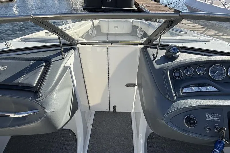 Slide: The Image of 2008 Cobalt 202 boat dashboard with gauges and steering wheel, docked by the water. - 25