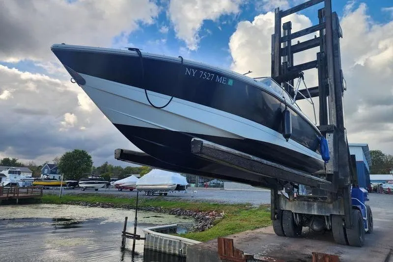 Slide: The Image of 2008 Cobalt 202 boat lifted by forklift near a lake under cloudy sky. - 6