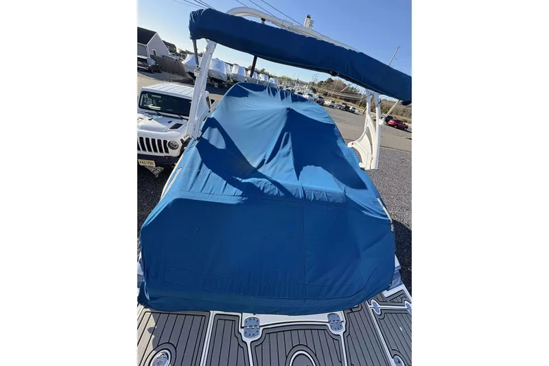 Slide: The Image of Covered 2020 Monterey M-65 boat with blue tarp, parked near a white vehicle. - 26