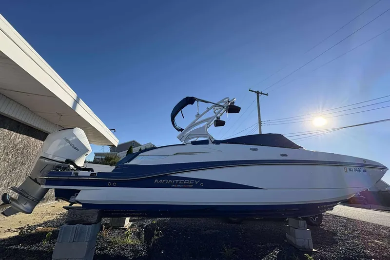 Slide: The Image of 2020 Monterey M-65 boat with Mercury engine, parked outdoors under clear blue sky. - 3