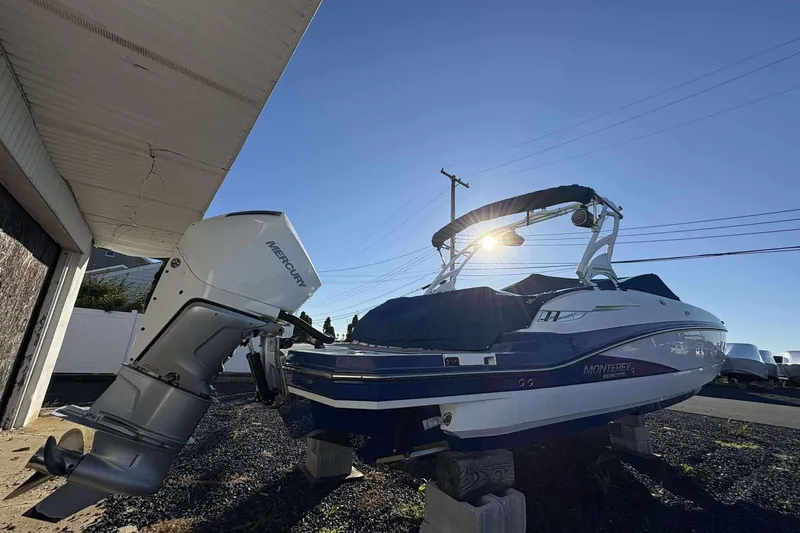 Slide: The Image of 2020 Monterey M-65 boat with Mercury engine, parked outdoors under clear sky. - 4