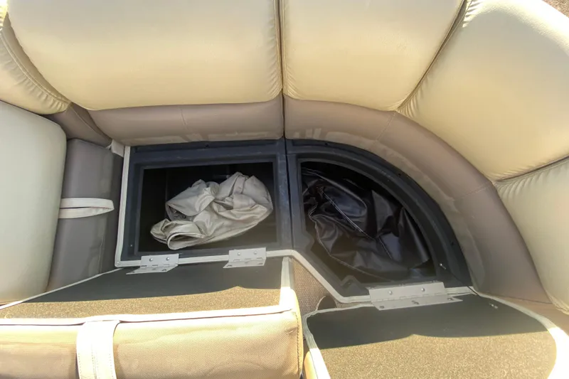 Slide: The Image of 2018 Hampton 2485 SE boat storage compartment with beige seating and stored covers. - 22