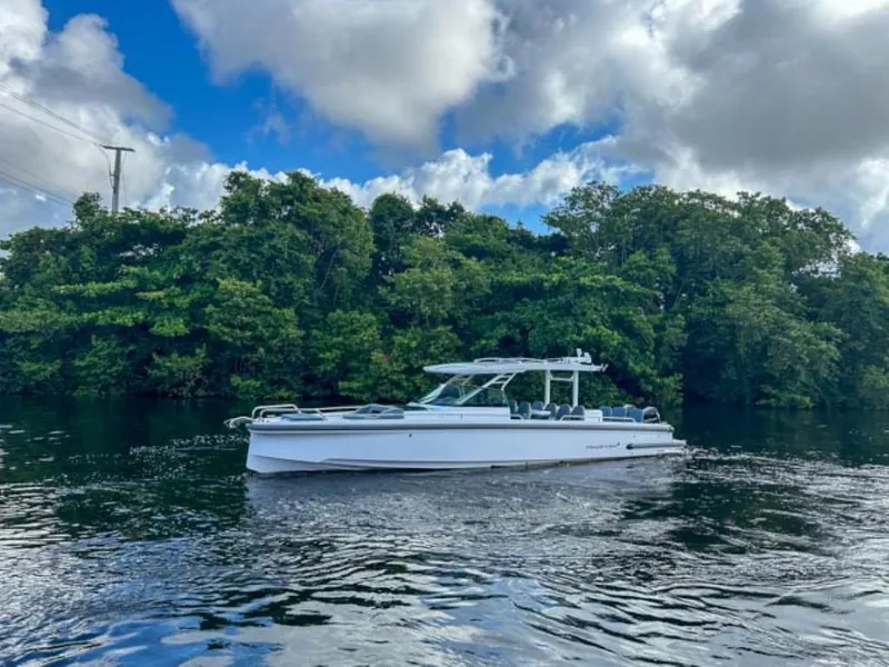 Slide: The Image of 2024 Axopar 37 Sun Top boat cruising on a serene waterway with lush greenery. - 3
