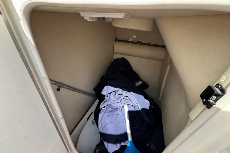 Slide: The Image of Storage compartment in 2006 Sea Ray 290 SLX boat with clothes and cleaning tools. - 38