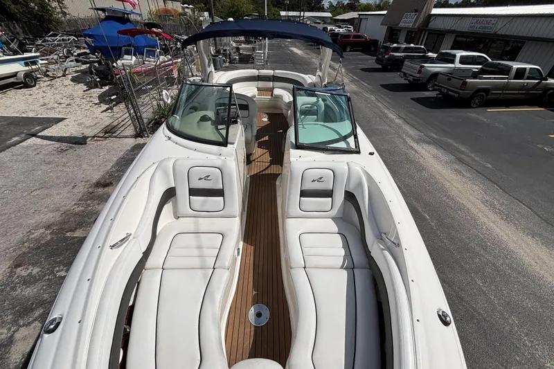 Slide: The Image of 2006 Sea Ray 290 SLX boat with white seating and wooden deck, parked outdoors. - 49
