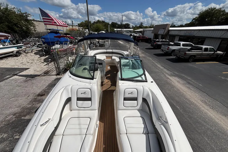Slide: The Image of 2006 Sea Ray 290 SLX boat with white seating, docked near a marina. - 50