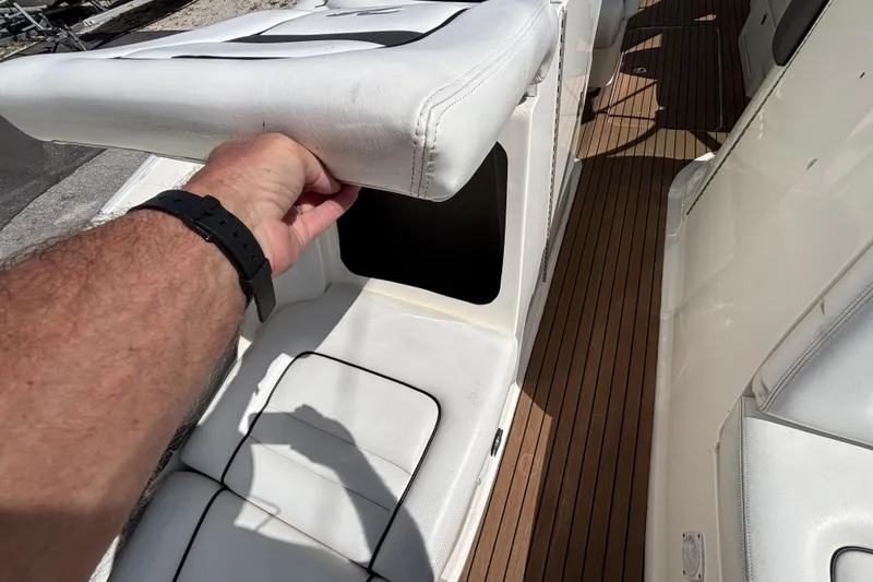 Slide: The Image of Hand lifting seat on 2006 Sea Ray 290 SLX boat, revealing storage compartment. - 55