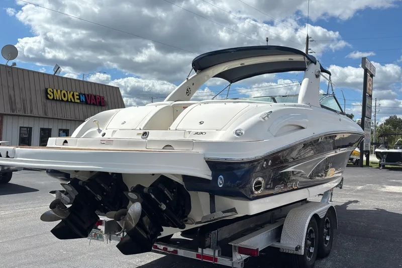 Slide: The Image of 2006 Sea Ray 290 SLX boat on trailer, parked near a store under cloudy sky. - 7