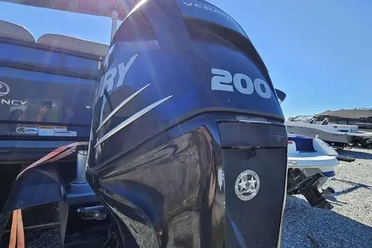 Slide: The Image of 2018 Regency 220 DL3 boat with Mercury 200 outboard engine, parked on gravel. - 4