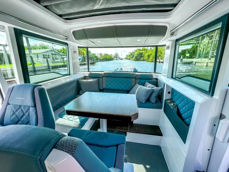 Slide: The Image of 2024 Axopar 37XC CROSS CABIN interior with seating and table, featuring large windows and modern design. - 9