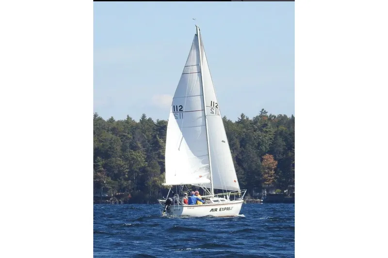 The Image of 1981 Catalina Capri 25 sailboat on a lake with forested shoreline. - 0