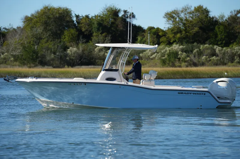 Slide: The Image of 2024 Grady-White Fisherman 236 boat cruising on calm water near a lush shoreline. - 8