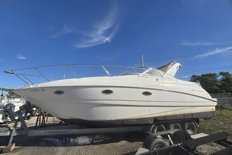 The Image of 2000 Larson Cabrio 330 Mid Cabin boat on trailer under clear blue sky. - 0