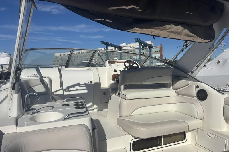 Slide: The Image of 2000 Larson Cabrio 330 Mid Cabin boat interior with seating and helm, under sunny skies. - 11