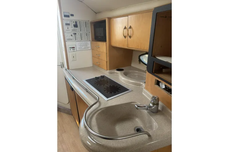 Slide: The Image of 2000 Larson Cabrio 330 Mid Cabin kitchen with stove, sink, and wooden cabinetry. - 25