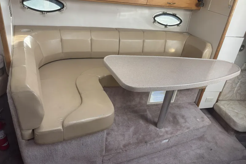 Slide: The Image of 2000 Larson Cabrio 330 Mid Cabin interior with beige seating and table. - 29