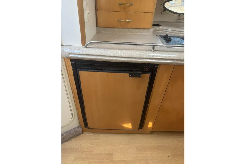Slide: The Image of 2000 Larson Cabrio 330 Mid Cabin kitchen with wooden cabinets and compact fridge. - 30