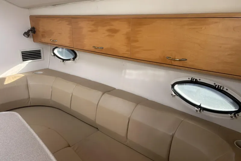 Slide: The Image of Interior of 2000 Larson Cabrio 330 Mid Cabin with beige seating and wooden cabinets. - 31