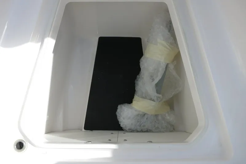 Slide: The Image of 2025 Robalo R250 Center Console storage compartment with bubble-wrapped item inside. - 18