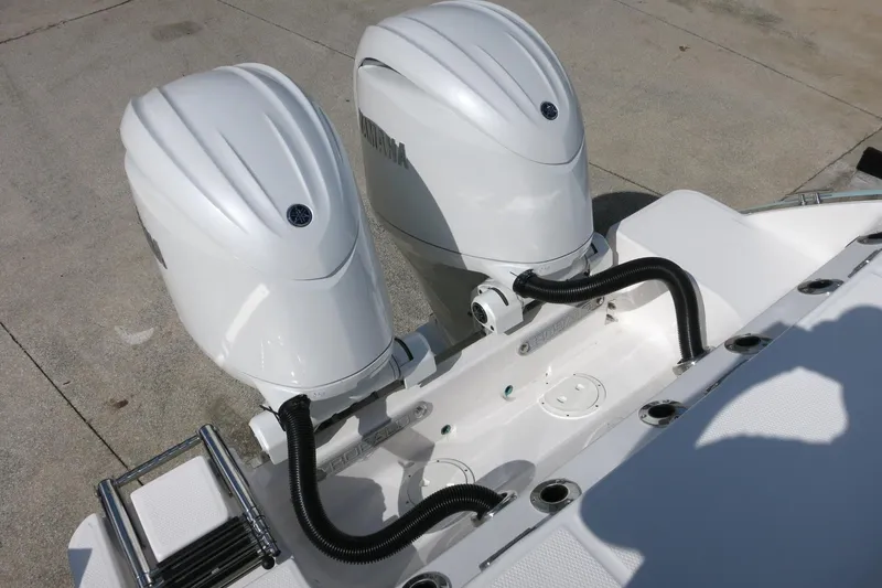 Slide: The Image of 2025 Robalo R250 Center Console with dual outboard engines, docked on concrete surface. - 32