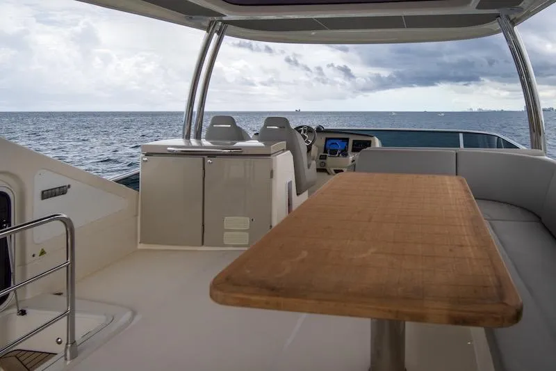 Slide: The Image of Luxurious 2023 Absolute 62 Fly yacht interior with ocean view, featuring a wooden table and seating. - 21