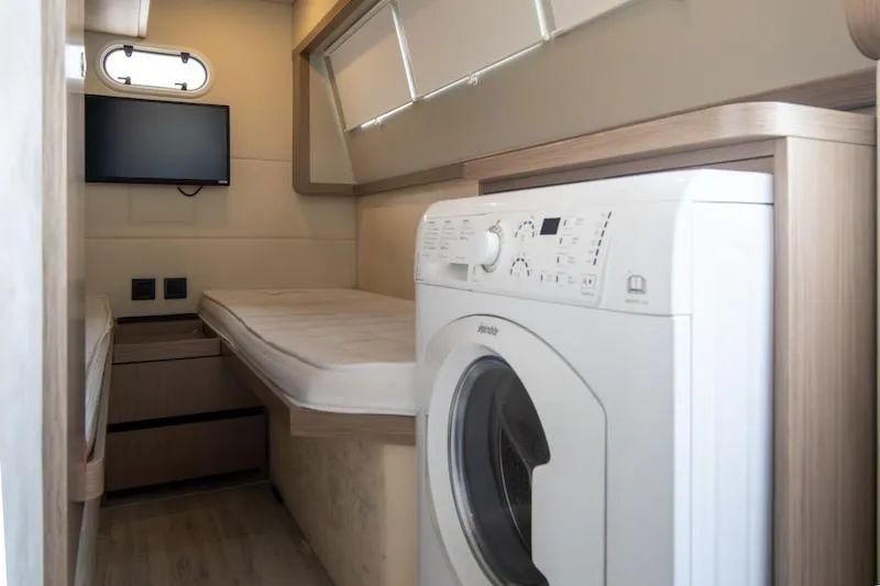 Slide: The Image of 2023 Absolute 62 Fly yacht interior with bed, TV, and washing machine. - 67