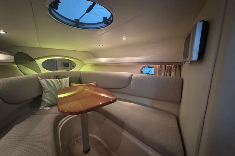 Slide: The Image of Interior of 2004 Four Winns 268 Vista boat, featuring cozy seating and a wooden table. - 10