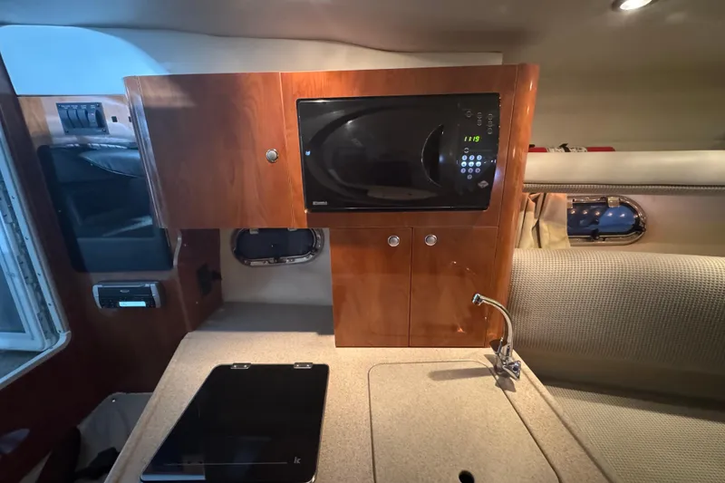 Slide: The Image of 2004 Four Winns 268 Vista cabin with microwave, sink, and wooden cabinetry. - 13