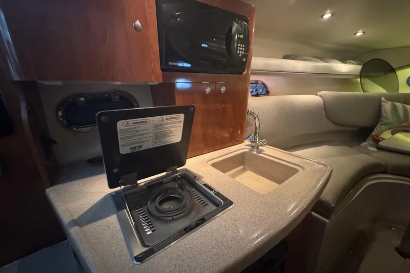 Slide: The Image of 2004 Four Winns 268 Vista boat interior with kitchenette, stove, sink, and microwave. - 15