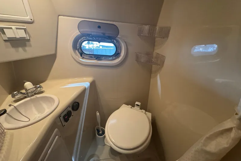 Slide: The Image of 2004 Four Winns 268 Vista boat bathroom with sink, toilet, and porthole window. - 16