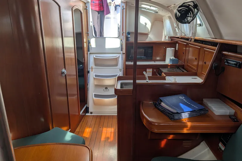 Slide: The Image of Interior of 2001 Beneteau Oceanis 331 sailboat with wood finish and compact kitchen. - 2